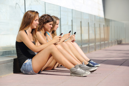 Group of three teenager girls typing on the mobile phone